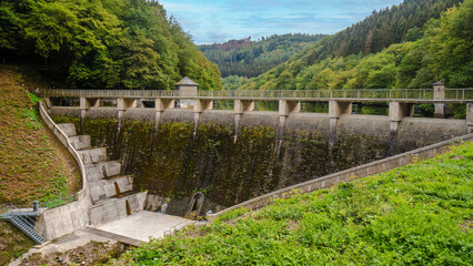 Concrete dam retaining water in artificial lake surrounded by forest