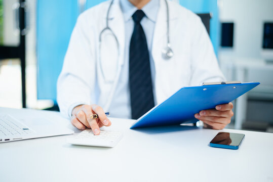 Healthcare costs and fees concept.Hand of smart doctor used a calculator and smartphone, tablet for medical costs at hospital