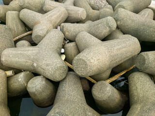 テトラポットとも呼ばれる消波ブロックが設置されている海沿いの防波堤のイメージ