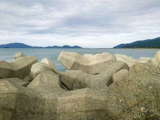 テトラポットとも呼ばれる消波ブロックが設置されている海沿いの防波堤のイメージ