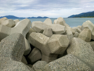 テトラポットとも呼ばれる消波ブロックが設置されている海沿いの防波堤のイメージ