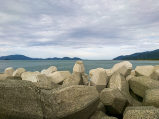 テトラポットとも呼ばれる消波ブロックが設置されている海沿いの防波堤のイメージ