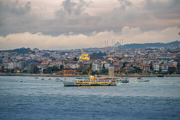 Obraz premium Evening view from the sea of the Maiden's Tower island, Ayazma Mosque, and the hilltop Çamlıca Mosque, on the Asian side of the Bosphorus Strait in Istanbul, Turkey.