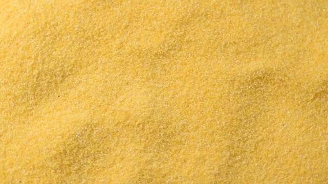 Close-up of yellow corn flour texture, finely ground and natural, symbolizing organic food ingredients, gluten-free cooking, and traditional cuisine preparation.Rotating video.