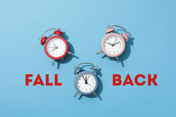 Three alarm clocks in red, pink, and blue on a blue background