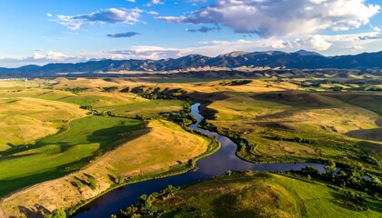 Aerial view of a river winding through rolling hills towards distant mountains