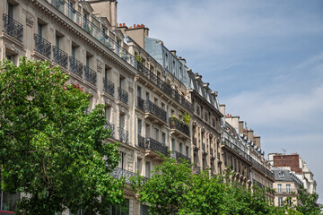 Fototapeta premium Haussmann-style residential facades in Paris a grand boulevard. Elegant limestone buildings illustrate classic 19th-century urban planning and city housing and real estate in paris and france.