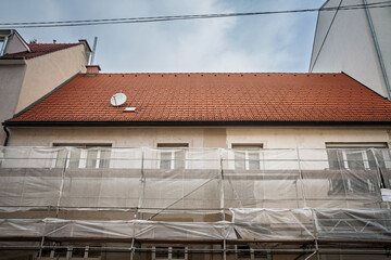 Residential building in Graz under renovation with scaffolding wrapped in mesh, fresh plaster patches and insulation work, illustrating construction activity and property upgrades in Austria.
