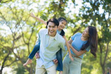 Naklejka premium Asian family enjoying a picnic in the park on a sunny weekend.