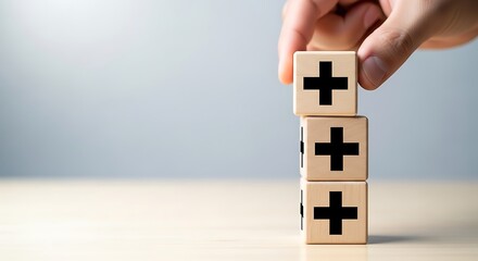 Hand stacking wooden blocks with plus signs, symbolizing growth, positivity, and added value