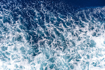 Marine splash texture with ocean waves and foam structure in dark blue clear water showing deep sea natural surface pattern
