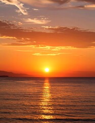Vibrant sunset over calm ocean waters, reflecting the sun's fiery glow
