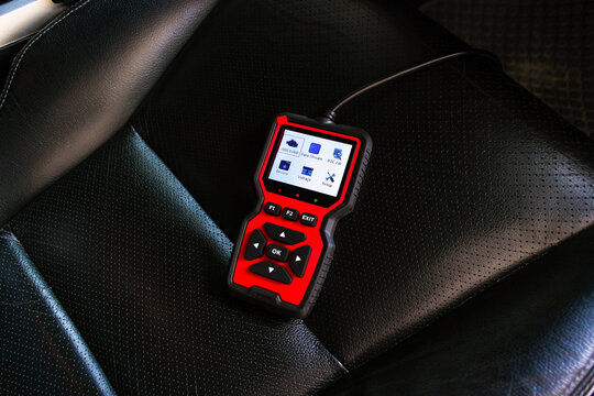 Automotive OBD2 diagnostic scanner on car seat, vehicle code reader and engine check tool for fault detection, car maintenance and repair technology, diagnostic equipment for auto service