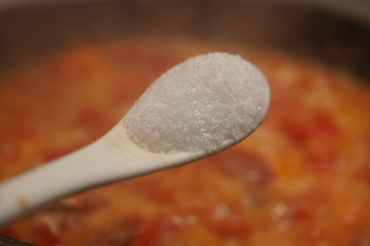 Adding salt to a sauce to balance flavor during cooking