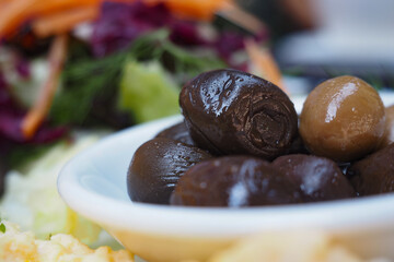 Olives served on a plate with colorful salad