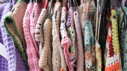 Colorful crochet clothes displayed in a thrift shop