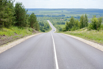an asphalt road among hills and trees
