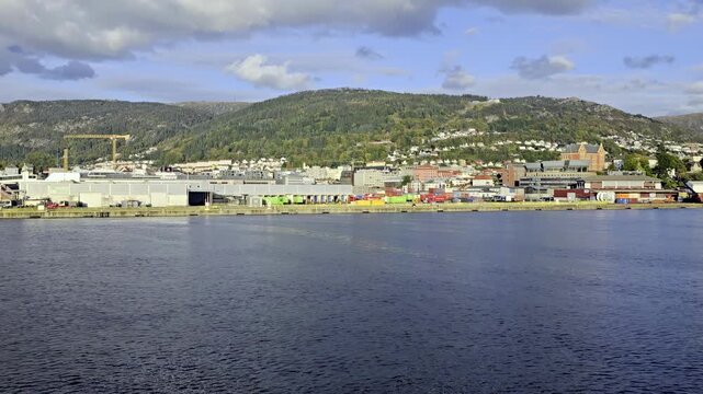 View from sea showing Posten Bring terminal with green containers and company logos in Bergen harbor
