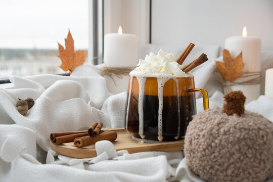 Autumn hygge Orange Cup of warm coffee autumn leaves on table against raindrops are running down the glass in window. Cozy fall still life footage burning candles. Thanksgiving and Halloween holiday