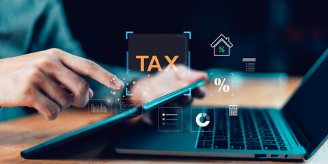 A person using a tablet and laptop for online tax calculation and financial analysis. Concept of digital taxation, accounting software, finance technology, and business data management.