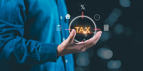 Person holding digital hologram with the word TAX surrounded by finance icons. Concept of online taxation, business accounting, financial planning, and modern technology for tax management.