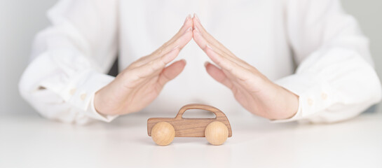 Woman hand cover cover car toy on table. Car insurance, warranty, repair, Financial, banking and money concept