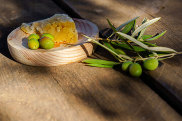 Freshly picked green olives, an olive branch, and rustic bread on a wooden surface, suggesting mediterranean cuisine and healthy eating