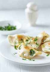 Dumplings with potato and cottage cheese stuffing (pierogi). Wooden background.	