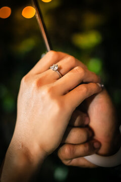 Foto ini menampilkan momen romantis yang penuh makna, dengan fokus pada sepasang tangan yang saling menggenggam erat di bawah cahaya hangat.