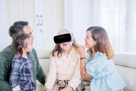 Happy Multi-Generational Asian Family Introducing Virtual Reality (VR) Headset to Senior Grandmother
