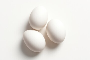 Three white eggs arranged in a neat triangular composition on pure white