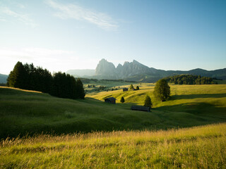 Beautiful sunrise with fields, cottages and mountains. Alpe di Siusi, Dolomites, Italy