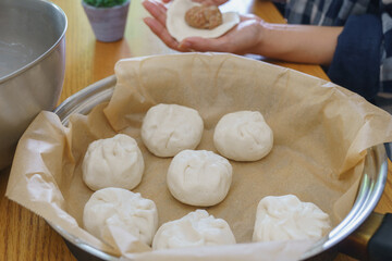 フライパンで肉まんを作る・肉まんを包む女性