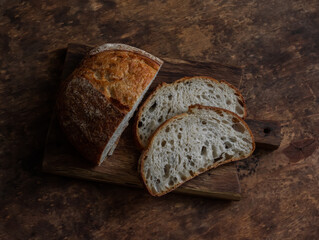 Sourdough homemade tartine bread on a wooden cutting board on a wooden background, top view
