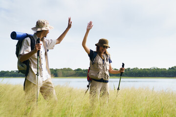 Asian man and woman happily high-fiving each other after reaching their hiking destination in a...