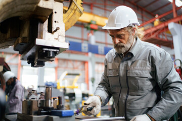 Skilled worker operating metal sheet machine in factory.