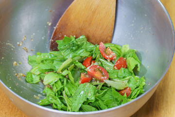 ボウルの中のサラダを木べらで混ぜる｜レタスとトマトのサラダ