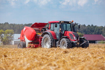 Tractor with bale machine for harvesting straw in the field and making large round bales....