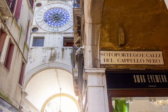 Venice, Italy - June 17, 2025: The famous clock face of St. Mark&rsquo;s Clock Tower is seen from the narrow Sotoportego e Calle del Cappello Nero street in Venice, Italy. 