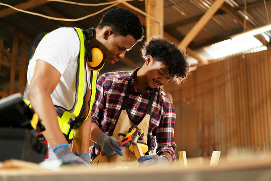 African American carpenters inspecting wood and reviewing documents.