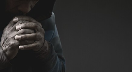 man praying to god with hands together Caribbean man praying with black grey background with people...