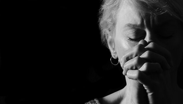 woman praying with hands together on grey black background with people stock image stock photo