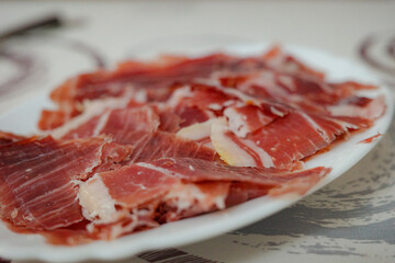 Slices of Iberian ham on a white plate, Spanish traditional food