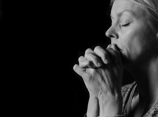 woman praying with hands together on grey black background with people stock image stock photo