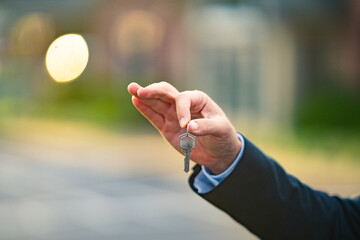 A realtor hands the keys after finalizing a property purchase. Homeowner holds keys to newly purchased apartment. A real estate agent shows house keys. Client receives keys for a residential property.