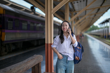 Fototapeta premium A woman is talking on her cell phone while standing at a train station