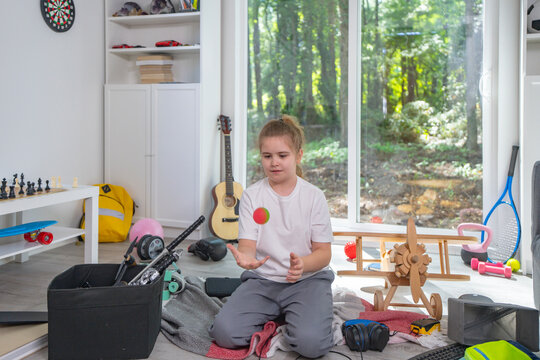 Child cleaning messy playroom at home. Kid organizing scattered toys on the floor. Kid helping tidy up children room. Boy cleaning untidy playroom interior. Funny child picking up toys in messy room.