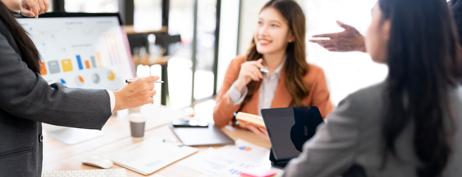 Asian businesswomen discussing a financial report and reviewing data during an informal business meeting in the office.