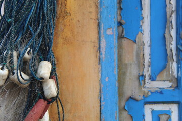 Nautical net and weathered wooden panel with peeling blue paint. Ideal for maritime, rustic, fishing, or texture-themed visual content