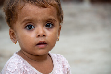 Adorable Pakistani baby girl in pink dress looking at camera with innocent eyes